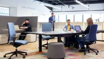 People sat on ergonomic task chairs at wooden desks working