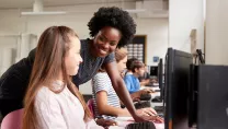 Image of a teacher with a student who is on a computer at school. 