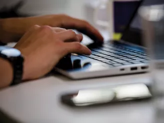 Hands typing on a laptop