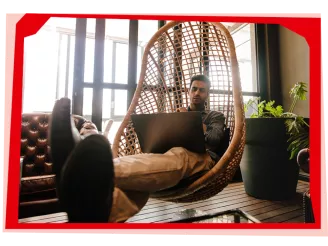 Man using laptop in hammock chair