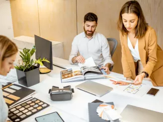 Space planners working at desk with fabric samples, colour swatches and laptops