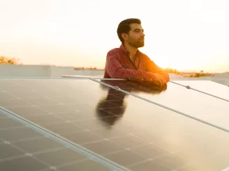 Technician looks into distance, leaninng on PV panels