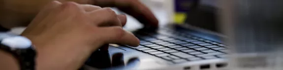 Hands typing on a laptop