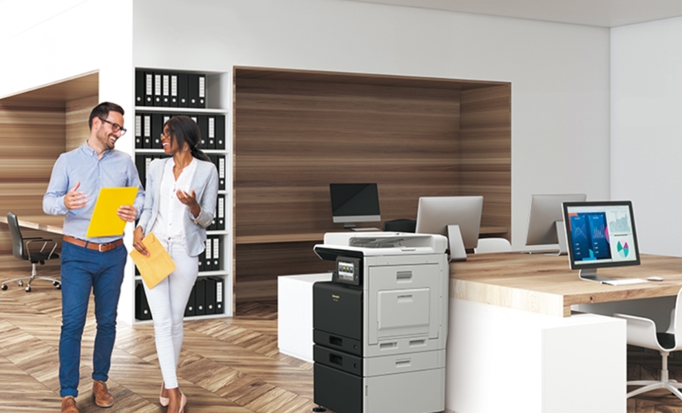 Two colleagues walking past a printer in the office