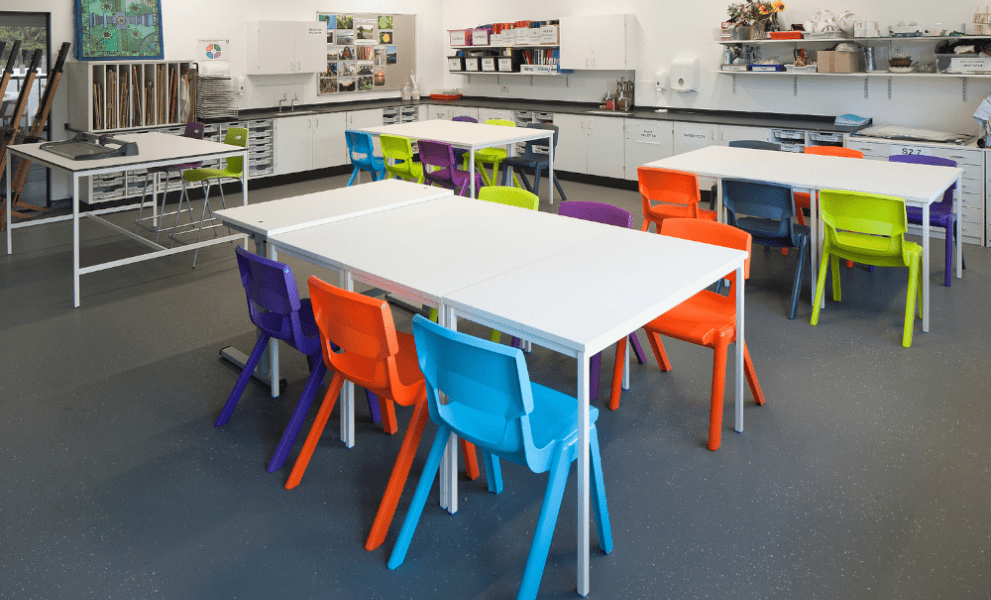 School desks in classroom with coloured chairs