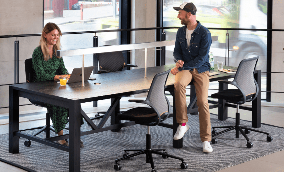 Man and woman sat at modern meeting room table with task chairs